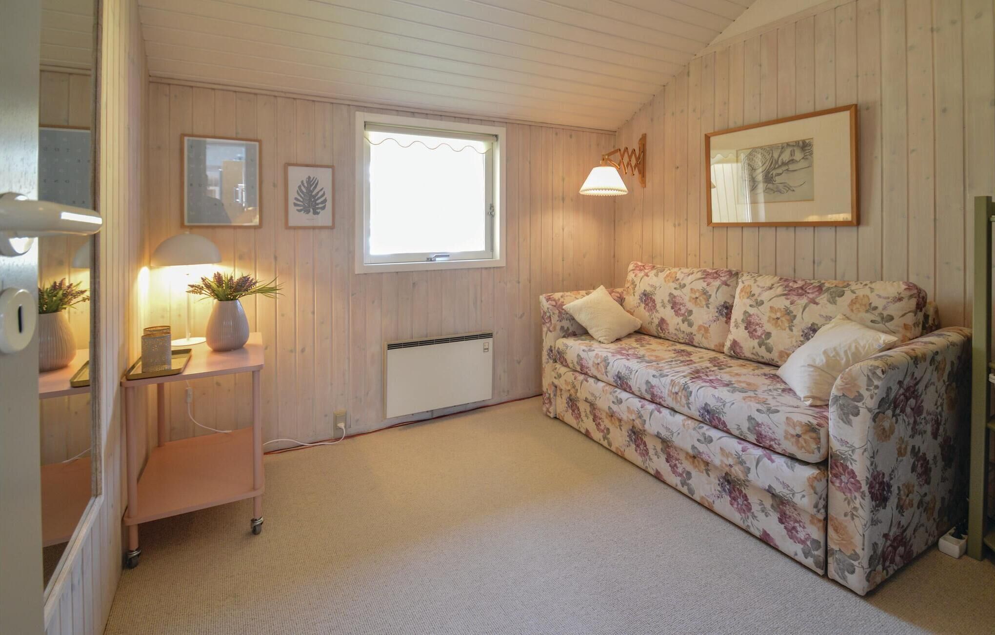 Een gezellige kamer met een bloemenbank, een kleine tafel met een lamp, een radiator en lijstwerken aan de wanden.