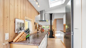 Una cocina moderna con paneles de madera, electrodomésticos de acero inoxidable y una isla central con diversos utensilios y una botella.