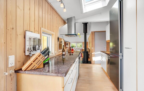 Una cocina moderna con paneles de madera, electrodomésticos de acero inoxidable y una isla central con diversos utensilios y una botella.