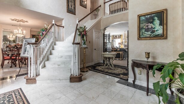 A grand foyer with a marble staircase, a chandelier, and a dining area with wooden furniture. - ENJOY RESORT  STYLE LUXURY ACCOMMODATIONS AT THE ESTATE HOME (Mansfield)