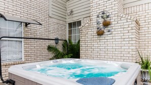 A hot tub in a covered outdoor area with a brick wall, a window, and potted plants. - ENJOY RESORT  STYLE LUXURY ACCOMMODATIONS AT THE ESTATE HOME (Mansfield)