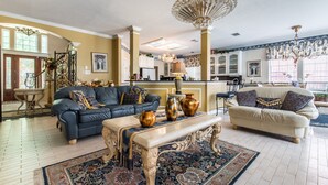 A spacious living room with a large chandelier, two sofas, a coffee table, and a patterned rug. - ENJOY RESORT  STYLE LUXURY ACCOMMODATIONS AT THE ESTATE HOME (Mansfield)