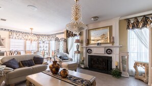 A spacious living room with a fireplace, elegant furniture, and a chandelier. - ENJOY RESORT  STYLE LUXURY ACCOMMODATIONS AT THE ESTATE HOME (Mansfield)