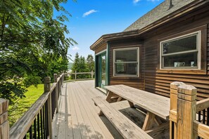 A wooden deck with a picnic table, a wooden fence, and a building with large windows.