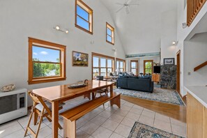 A spacious living area with a dining table, sofas, and large windows offering views of the outdoors.