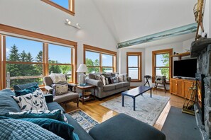 A spacious living room with a fireplace, large windows, and a cozy seating area.