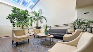 Een moderne loungehoek met leren banken, een bijzettafeltje en potplanten.