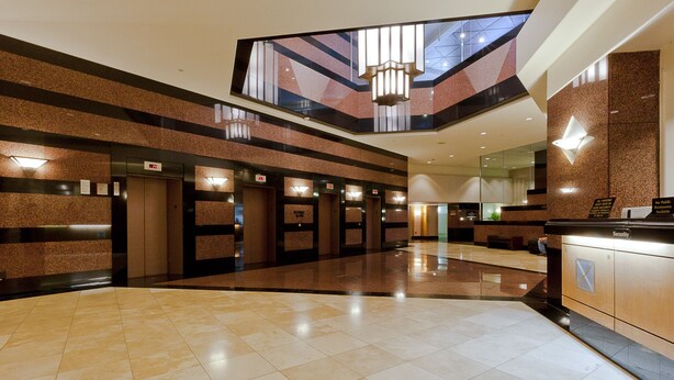 Een moderne hotel lobby met een hoge plafond, een centrale kroonluchter, en een uitzicht door een glazen dak.