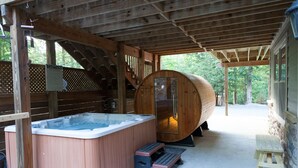 Une cabane en bois dotée d’un bain à remous, d’un escalier en bois et d’une véranda couverte.