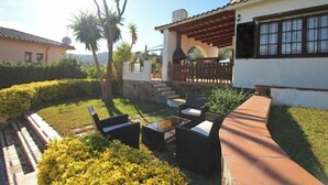 Un espace patio aménagé avec du mobilier d’extérieur, une pergola et une vue sur une maison à l’extérieur blanc et au toit rouge.