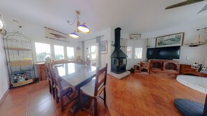 Un vaste espace de vie comprenant une grande table à manger en bois, une cheminée et un téléviseur.