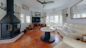 Un salon avec une cheminée, un canapé, un téléviseur et un ventilateur de plafond.