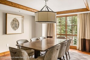 Enjoy meals in this dining area with a large table and six chairs, surrounded by a wooden ceiling and a pendant light.