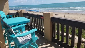 A beach view from a balcony with turquoise chairs and a 'No Smoking' sign.