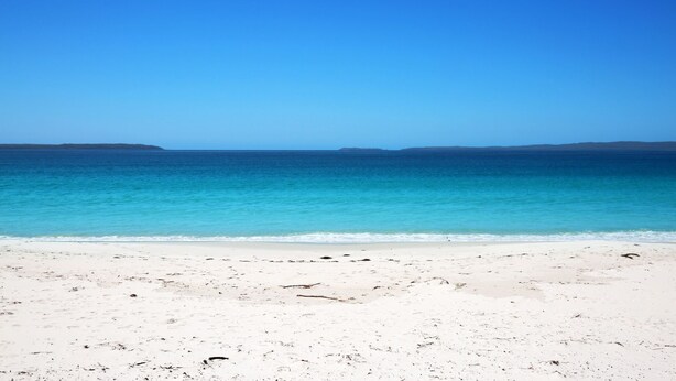 Une plage de sable blanc bordée d’une eau d’un bleu cristallin.