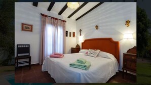 Une chambre à coucher avec un lit, des tables de chevet, une chaise et une fenêtre avec des rideaux.