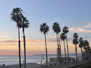 A beach with palm trees and a stone building with a clock tower.