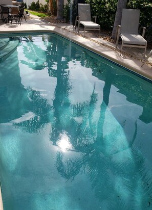 Une piscine aux eaux cristallines, bordée de carreaux, entourée d’un espace de détente extérieur et de verdure.