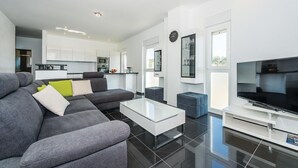 A modern living room with a grey sofa, a glass coffee table, and a flat-screen TV. - Beach front home in Brodarica with house sea view (Brodarica)