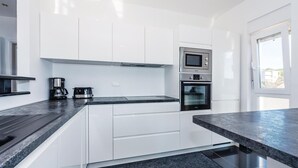 A modern kitchen with white cabinets, a built-in oven, a microwave, and a coffee maker. - Beach front home in Brodarica with house sea view (Brodarica)