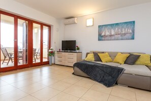 A living room with a sofa, a TV, and a painting on the wall.