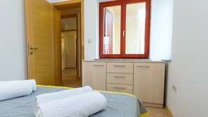 Un dormitorio con cama, armario y ventana con persianas.