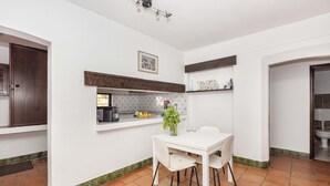 Una cocina compacta con una mesa y sillas blancas, una ventana con vistas y una puerta de madera.