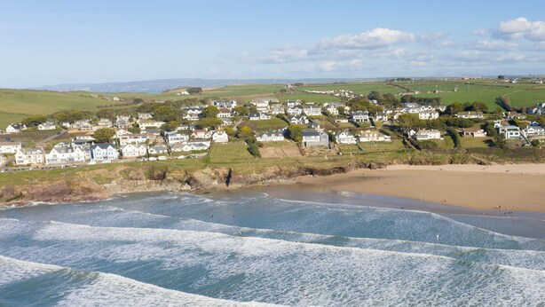 A coastal town with white houses, a sandy beach, and waves crashing onto the shore. - No 4 Pentire Rocks is a contemporary maisonette situated in New Polzeath. (Wadebridge)