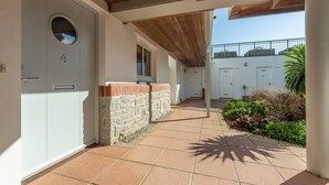A covered outdoor area with a tiled floor, a stone wall, and a door with a window. - No 4 Pentire Rocks is a contemporary maisonette situated in New Polzeath. (Wadebridge)