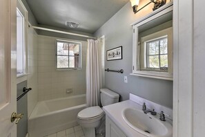 Un baño con bañera, inodoro, lavabo y ventana con vistas.