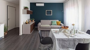 Un salon moderne comprenant un coin repas, un canapé et un petit espace cuisine.