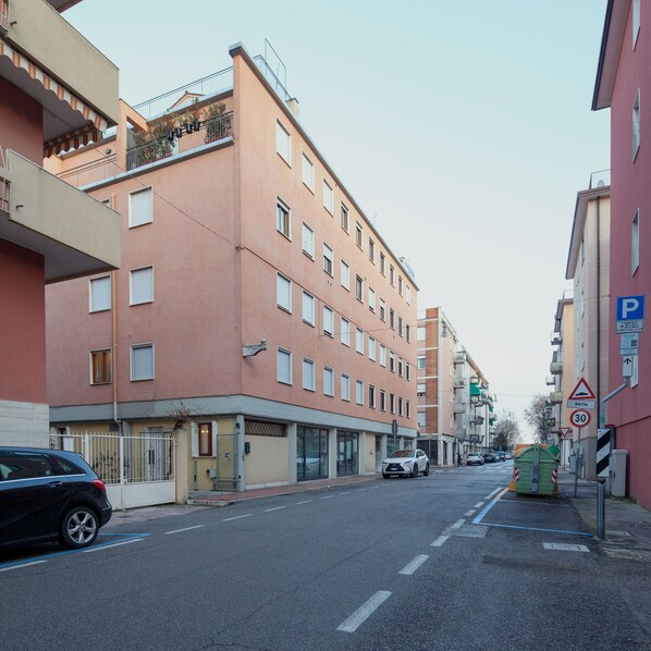 A multi-story building with balconies, a parking sign, and a speed limit sign.