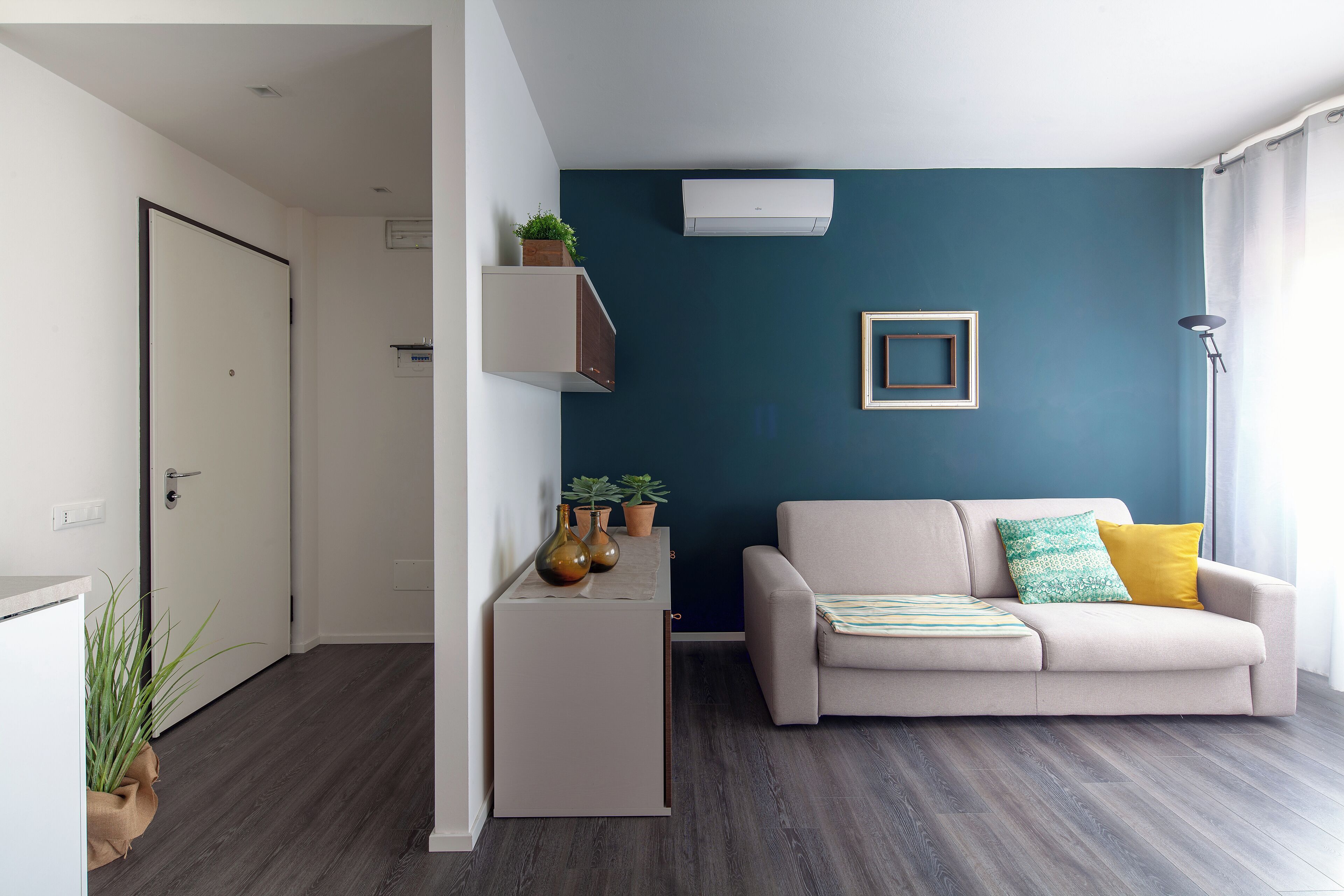 A modern living room with a sofa, a coffee table, and a wall-mounted air conditioner.