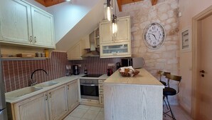 Eine Küche mit Holzausbau, einer Steinwand, einer Uhr und einer kleinen Kochinsel mit Stühlen.