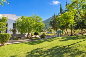 A well-maintained grassy area with trees, benches, and a modern building with large windows.