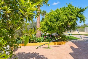 A garden with a variety of plants, a palm tree, and a swing set. - Cubo's Casa María los Javieles / free wifi / private pool (Alhaurín el Grande)