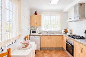 A kitchen with wooden cabinets, a microwave, a sink, and a stove. - Cubo's Casa María los Javieles / free wifi / private pool (Alhaurín el Grande)