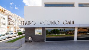 La entrada al Teatro Antonio Gama, con una vista despejada de los edificios circundantes y los coches aparcados.