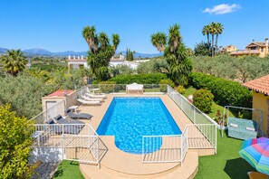 A rectangular swimming pool with a white deck and a white fence surrounding it.
