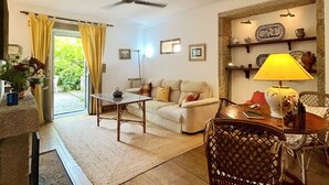 Ein Wohnzimmer mit einer Couch, einem Esstisch, einem Stuhl, einer Lampe und einem Deckenventilator.