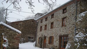 Un edificio de piedra con múltiples ventanas y un terreno cubierto de nieve.