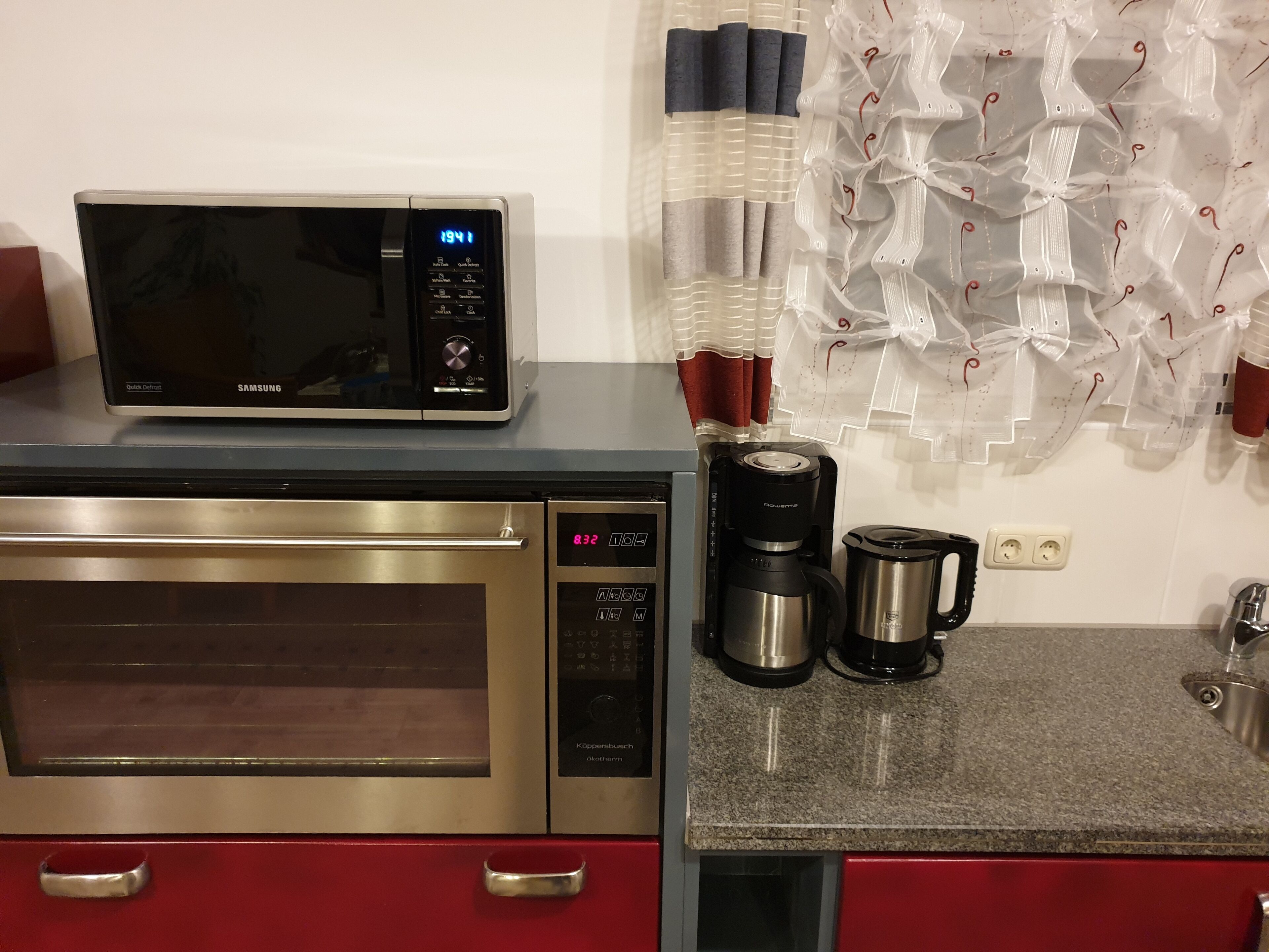 Une cuisine équipée d’un four à micro-ondes, d’une machine à café et d’une bouilloire, le tout posé sur un plan de travail en granit.