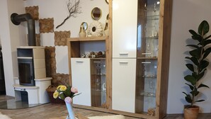 A modern living room with a wooden coffee table, a fireplace, a stone wall, and a cabinet with glass doors.