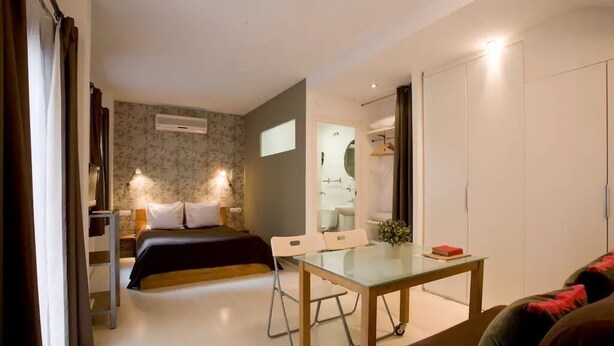 A bedroom with a bed, bedside table, and a small desk with a chair. There is a wardrobe and a mirror in the room. - Entire house in Outstanding location close to the City Center & Beach (Barcelona)