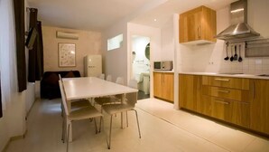 A modern kitchen with wooden cabinets, a stainless steel range hood, and a dining area with a white table and chairs. - Entire house in Outstanding location close to the City Center & Beach (Barcelona)