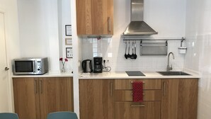 A modern kitchen with wooden cabinets, a stainless steel range hood, a microwave, a coffee maker, and a sink. - Entire house in Outstanding location close to the City Center & Beach (Barcelona)