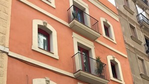 A multi-story building with balconies, arched windows, and a red door. - Entire house in Outstanding location close to the City Center & Beach (Barcelona)
