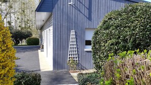 Un bâtiment moderne à l’extérieur gris, avec une porte blanche et une petite fenêtre.