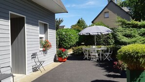 Une terrasse avec une table et des chaises, un banc et des plantes en pot.