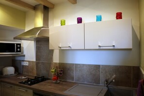 Une cuisine équipée d’un four à micro-ondes, d’une cuisinière et de placards.